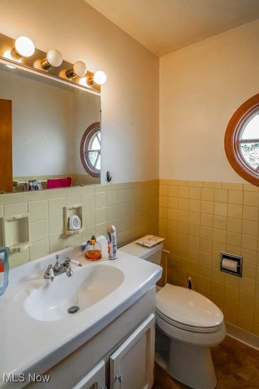 bathroom with vanity, tile walls, and toilet