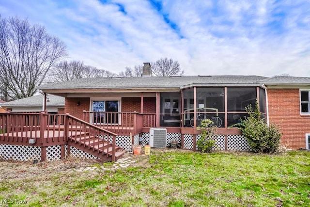 back of property with a wooden deck, a sunroom, a yard, and central AC