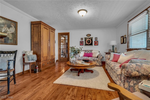 living room featuring light hardwood / wood-style flooring, ornamental molding, and a textured ceiling