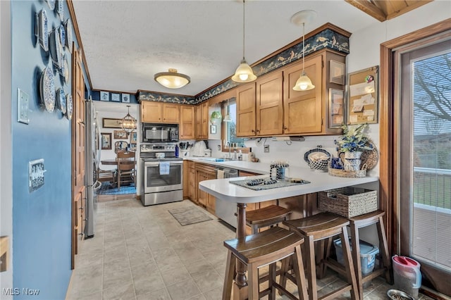 kitchen with a breakfast bar, sink, decorative light fixtures, kitchen peninsula, and stainless steel appliances