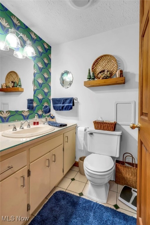 bathroom with vanity, toilet, tile patterned flooring, and a textured ceiling