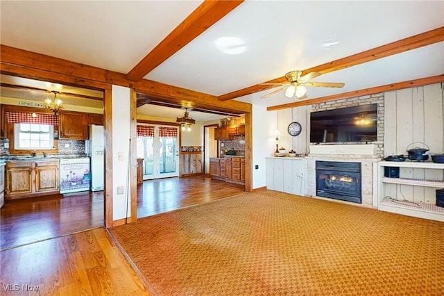 unfurnished living room with hardwood / wood-style flooring, ceiling fan with notable chandelier, and beamed ceiling