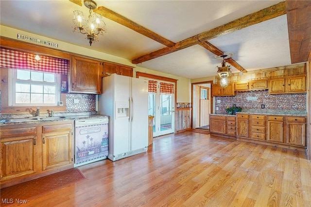 kitchen with pendant lighting, sink, white appliances, and a wealth of natural light