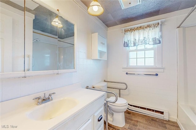 bathroom with tile walls, vanity, wood-type flooring, a baseboard radiator, and toilet