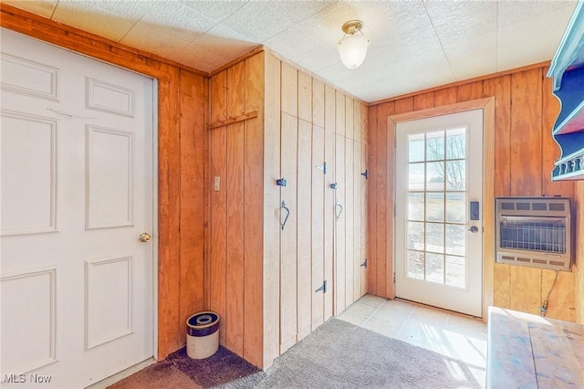 doorway with heating unit, light colored carpet, and wood walls