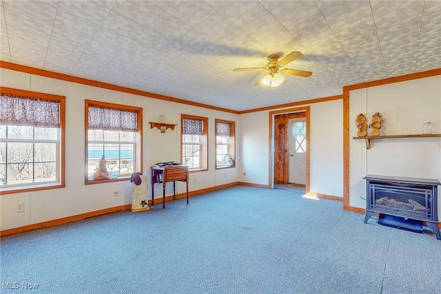 unfurnished living room with crown molding, ceiling fan, carpet flooring, and a wood stove