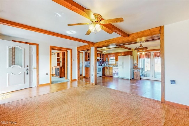 unfurnished living room with ceiling fan, carpet flooring, and beam ceiling