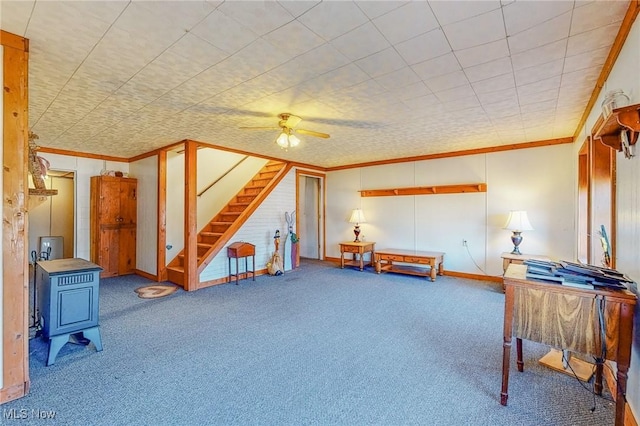 misc room with ornamental molding, carpet flooring, a wood stove, and ceiling fan