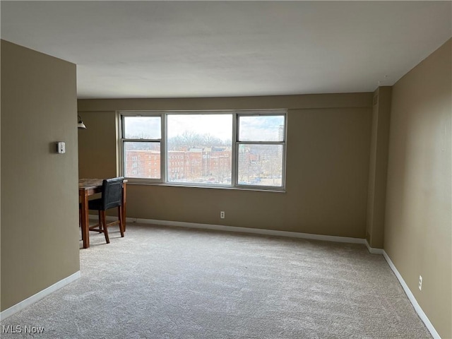 unfurnished room featuring light colored carpet and baseboards