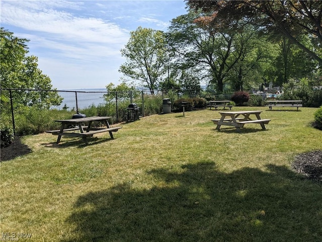 view of community featuring a lawn and fence