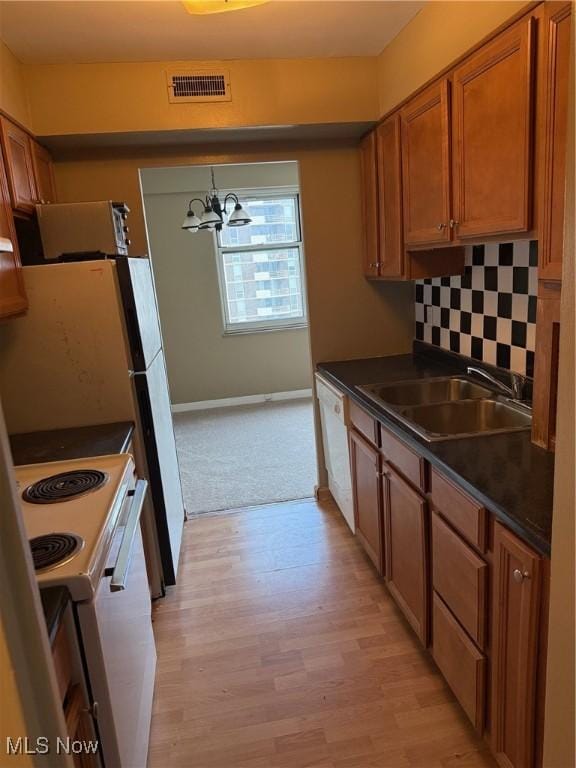 kitchen featuring tasteful backsplash, visible vents, brown cabinetry, dark countertops, and a sink