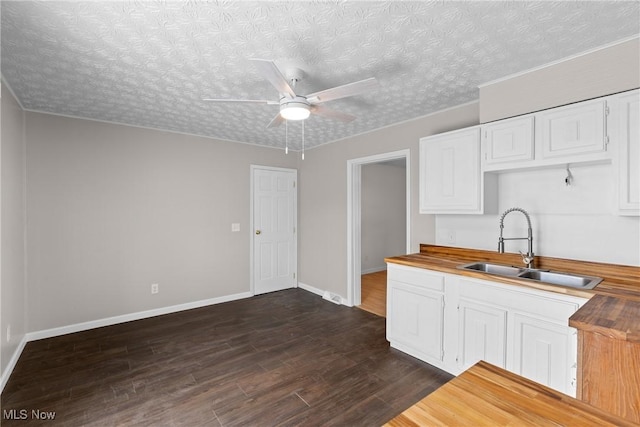 kitchen featuring dark wood-type flooring, wood counters, sink, ceiling fan, and white cabinets