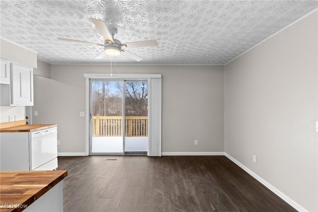 unfurnished dining area featuring dark wood-type flooring, a textured ceiling, and ceiling fan