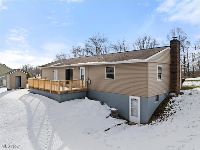 snow covered property featuring a wooden deck and central AC