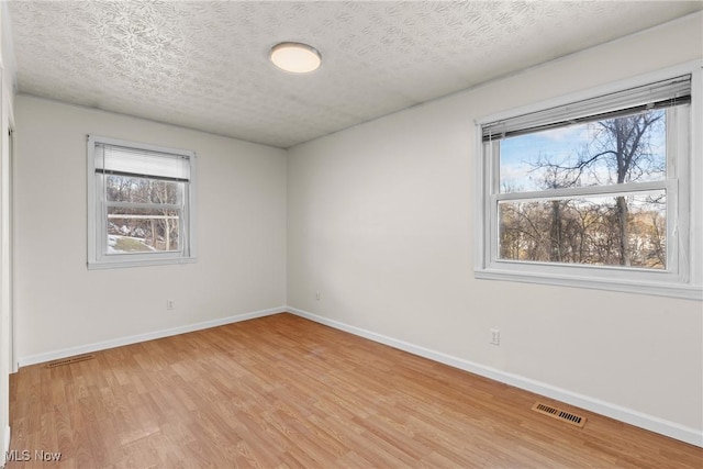 unfurnished room with light hardwood / wood-style flooring and a textured ceiling