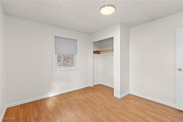 unfurnished bedroom featuring light hardwood / wood-style flooring, a closet, and a textured ceiling