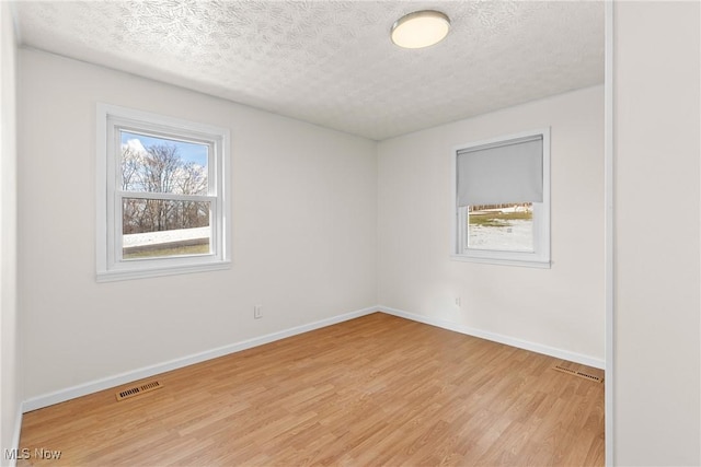 spare room featuring light hardwood / wood-style floors and a textured ceiling