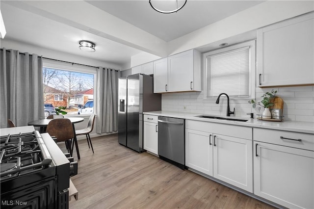 kitchen with white cabinetry, stainless steel appliances, light hardwood / wood-style floors, and sink