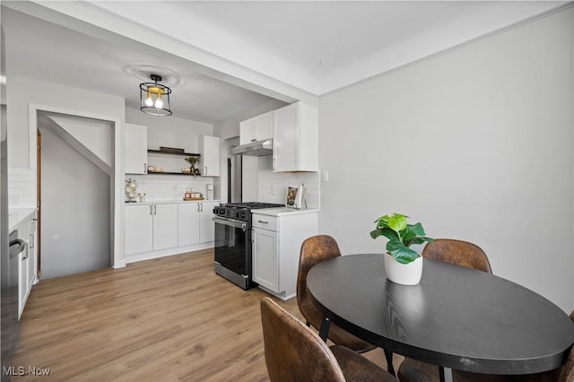 kitchen featuring white cabinetry, stainless steel gas range oven, tasteful backsplash, and light hardwood / wood-style flooring