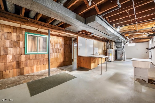 basement featuring gas water heater, heating unit, and wooden walls