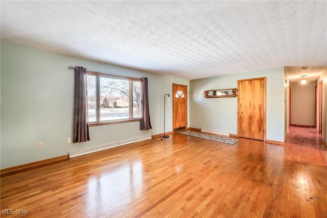 unfurnished room featuring wood-type flooring, a textured ceiling, and baseboard heating