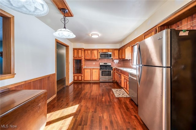 kitchen with appliances with stainless steel finishes, decorative light fixtures, sink, dark hardwood / wood-style flooring, and decorative backsplash