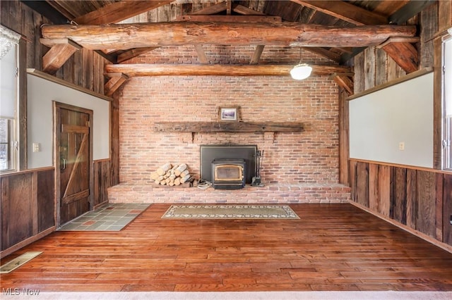 unfurnished living room with hardwood / wood-style flooring, a wood stove, and wooden walls