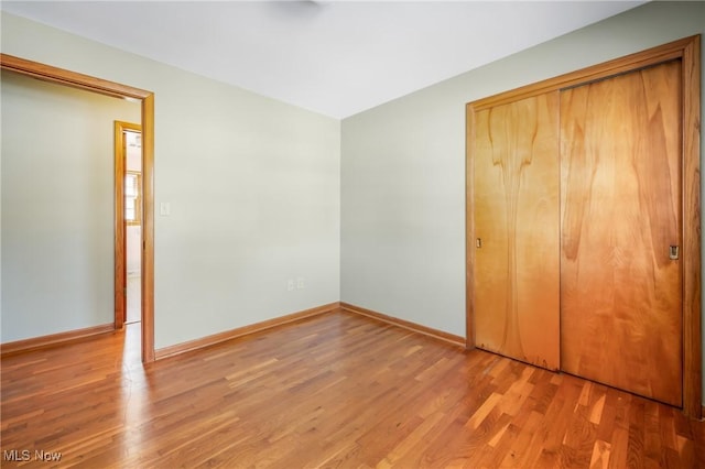 unfurnished bedroom with a closet and light wood-type flooring