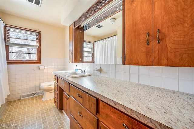 bathroom featuring tile patterned flooring, vanity, tile walls, and toilet