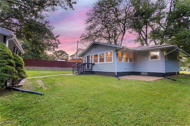 back house at dusk featuring a yard and a patio area