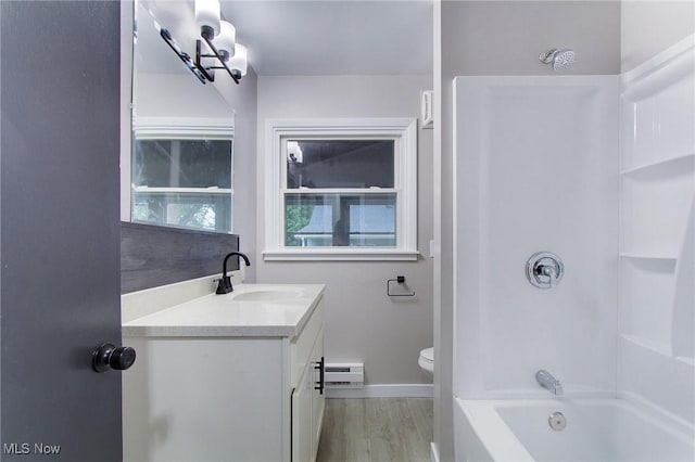 full bathroom with a baseboard heating unit, hardwood / wood-style floors, vanity, shower / washtub combination, and toilet