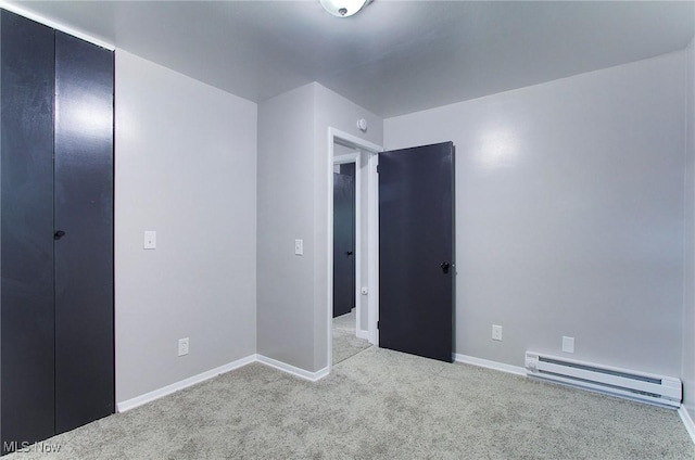 unfurnished bedroom with light carpet and a baseboard heating unit