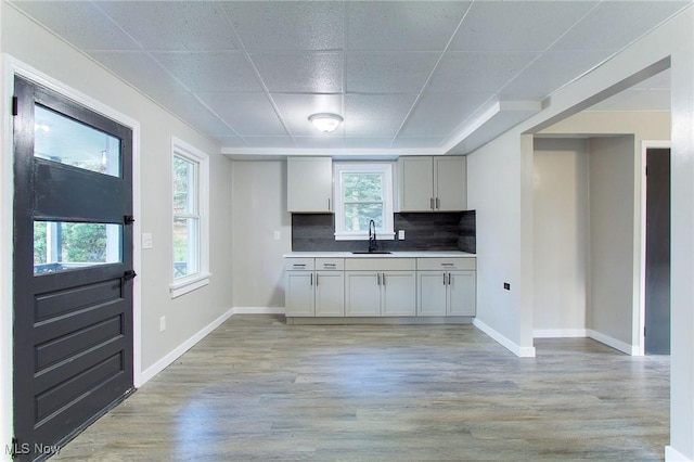 kitchen with a paneled ceiling, sink, decorative backsplash, and light wood-type flooring