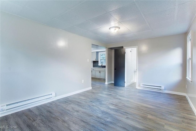 spare room with a paneled ceiling, sink, hardwood / wood-style floors, and a baseboard heating unit