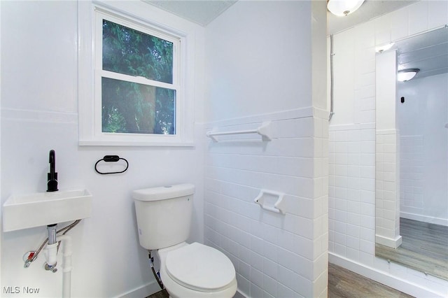 bathroom featuring toilet, hardwood / wood-style floors, and tile walls