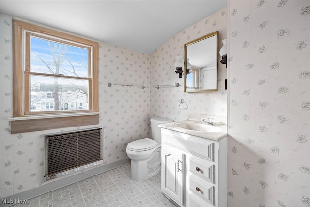 bathroom featuring vanity, heating unit, and toilet