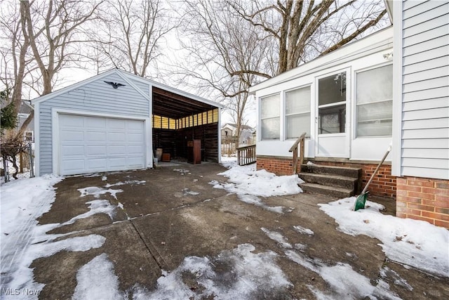 snow covered property featuring a garage and an outbuilding