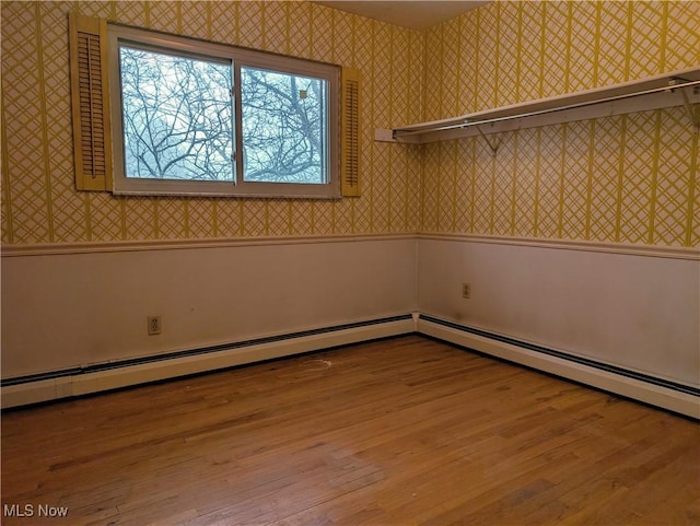 empty room featuring a baseboard heating unit and light hardwood / wood-style floors