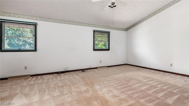 spare room with light colored carpet, plenty of natural light, and vaulted ceiling