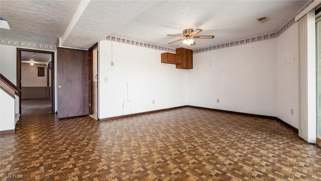 unfurnished room with ceiling fan, dark parquet flooring, and a textured ceiling