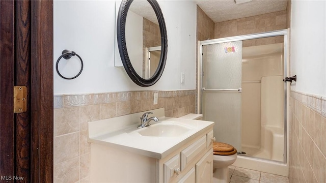 bathroom featuring tile patterned floors, toilet, a textured ceiling, tile walls, and vanity