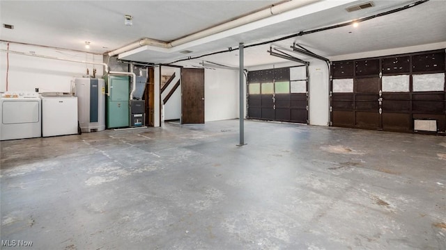 garage featuring heating unit, water heater, and washing machine and clothes dryer