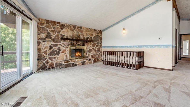 unfurnished living room featuring light carpet, a fireplace, lofted ceiling, and a textured ceiling