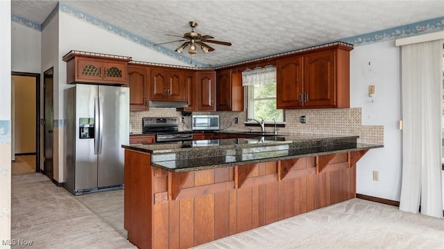 kitchen featuring ceiling fan, appliances with stainless steel finishes, kitchen peninsula, and dark stone counters