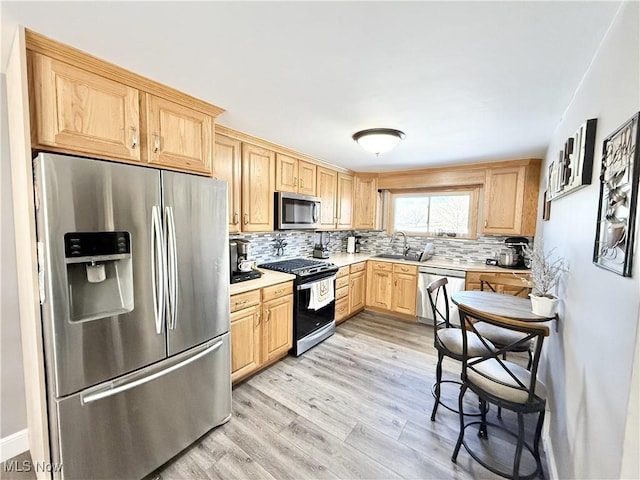 kitchen with sink, light hardwood / wood-style flooring, appliances with stainless steel finishes, decorative backsplash, and light brown cabinets