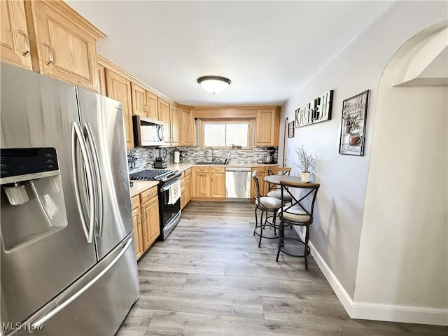 kitchen featuring stainless steel appliances, sink, light brown cabinets, and backsplash