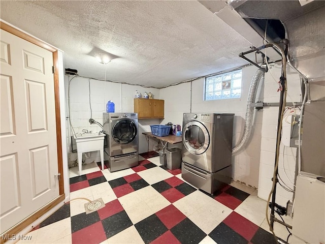 laundry room featuring sink, washing machine and dryer, cabinets, and a textured ceiling