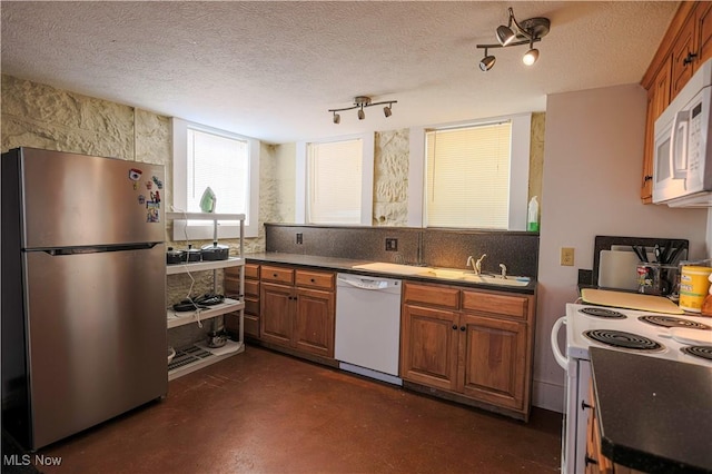 kitchen with decorative backsplash, white appliances, sink, and a textured ceiling