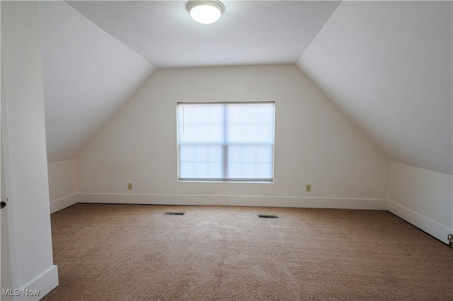 bonus room featuring vaulted ceiling and carpet