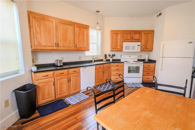 kitchen featuring wood-type flooring, sink, pendant lighting, and white appliances